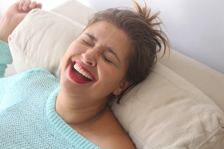 mujer feliz acostada en el sofá con aplicación de bergamota